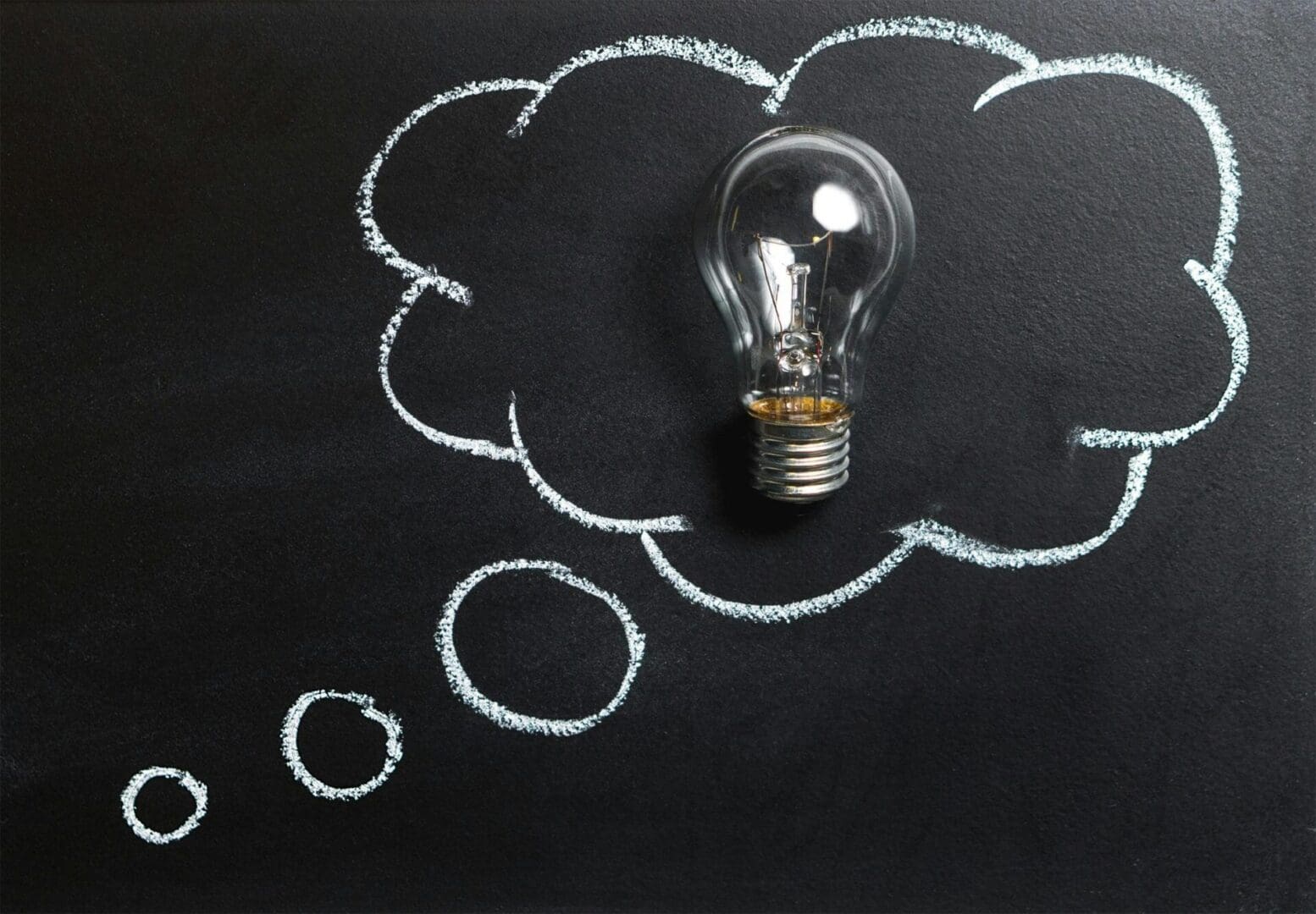 A light bulb sitting on top of a chalkboard.
